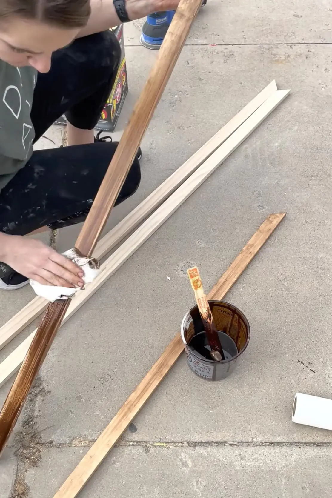 Wiping off stain with a paper towel while making a DIY bathroom mirror frame.